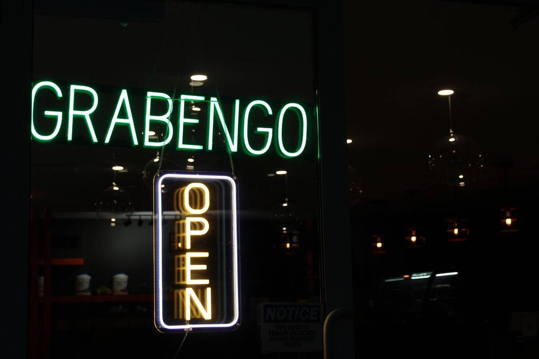 The green GRABENGO neon sign and a lit OPEN sign in the shop window